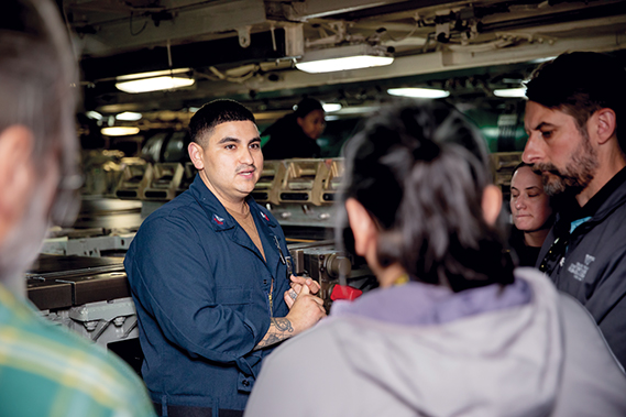 Torpedoman’s Mate 1st Class Chris Marquez, from Tucson, Ariz., describes working in a torpedo room to visitors during a chief executive officer and Educator Orientation Visit aboard the Ohio-class ballistic missile submarine USS Louisiana (SSBN 743), Aug. 7, 2024. (Navy photograph by PO1 Aaron T. Smith)