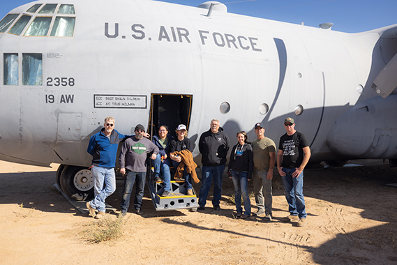 Team members from Edwards Air Force Base pose in front of the newly relocated C-130E, now on display outside the USAF Flight Test Museum. The complex movement from Edwards South Base included teamwork between Civil Engineering, Security Forces, Airfield Operations, and museum volunteers. (Air Force photo by Daniel Kelley)